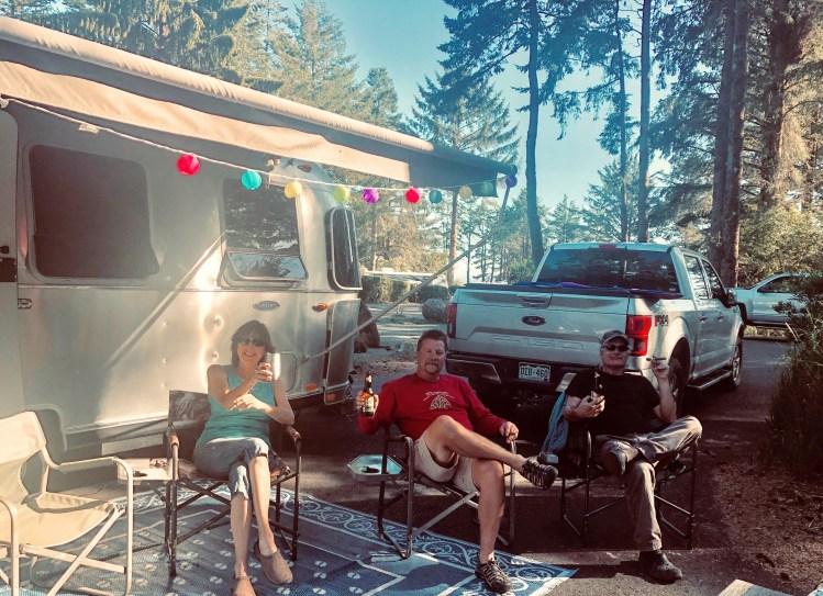 people drinking beer by a camper