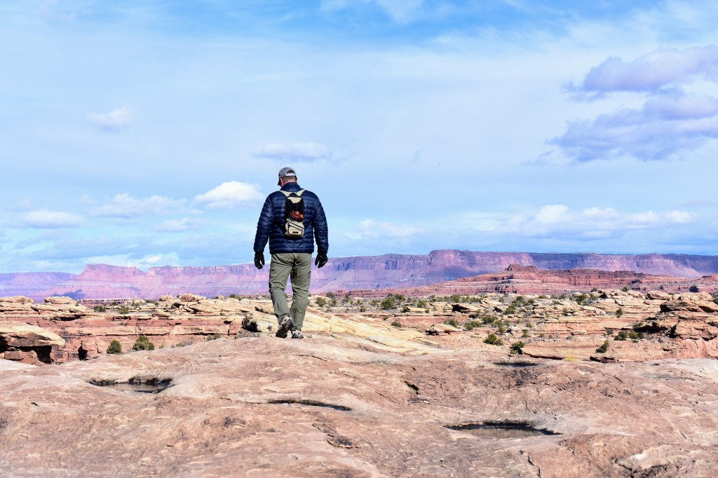 hiker on the slickrock looking out towards Island in the Sky
