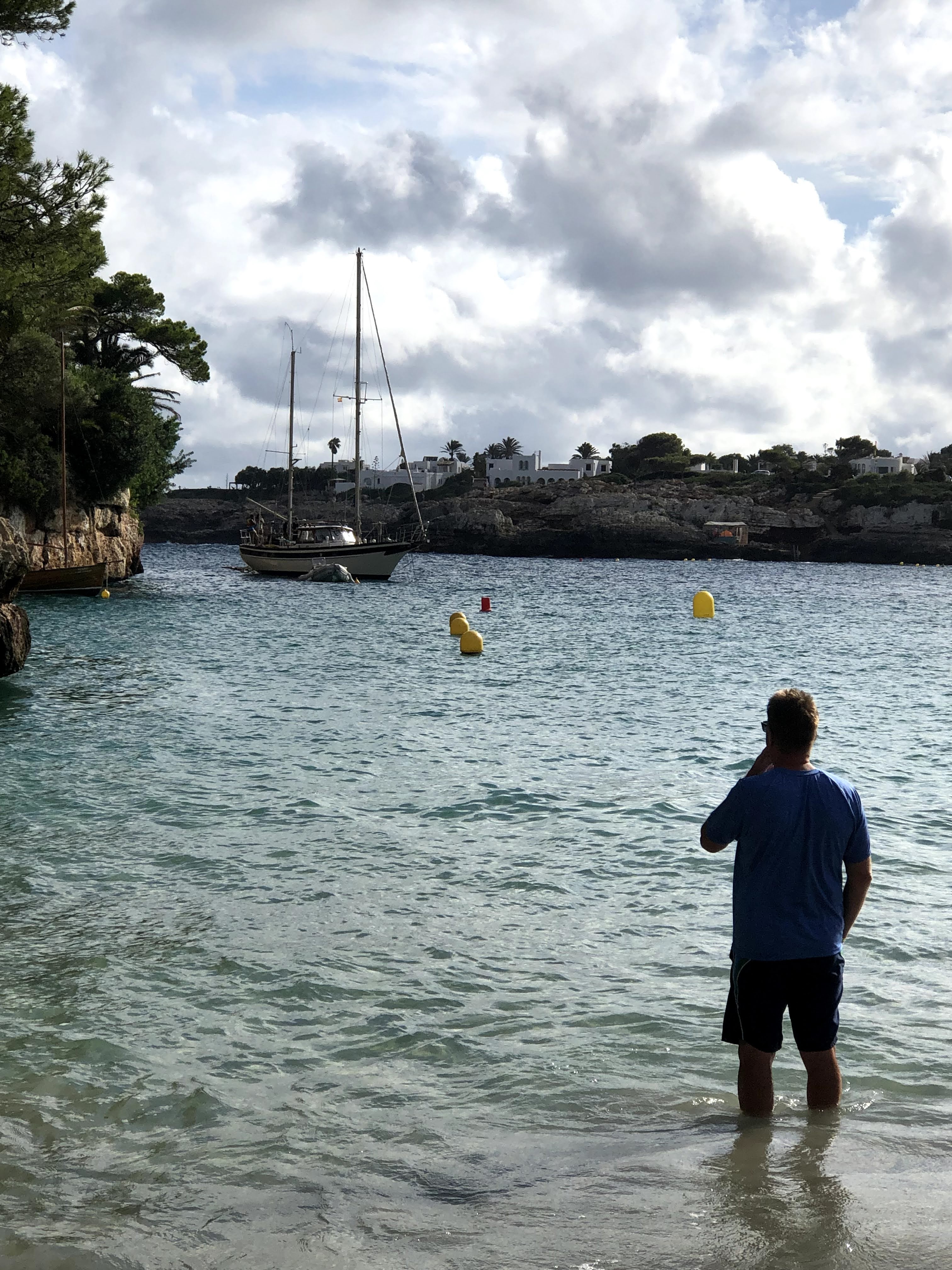 man on beach looking at sailboat