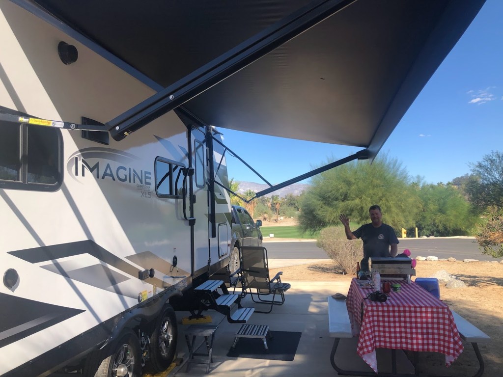camper trailer with picnic table and man waiving