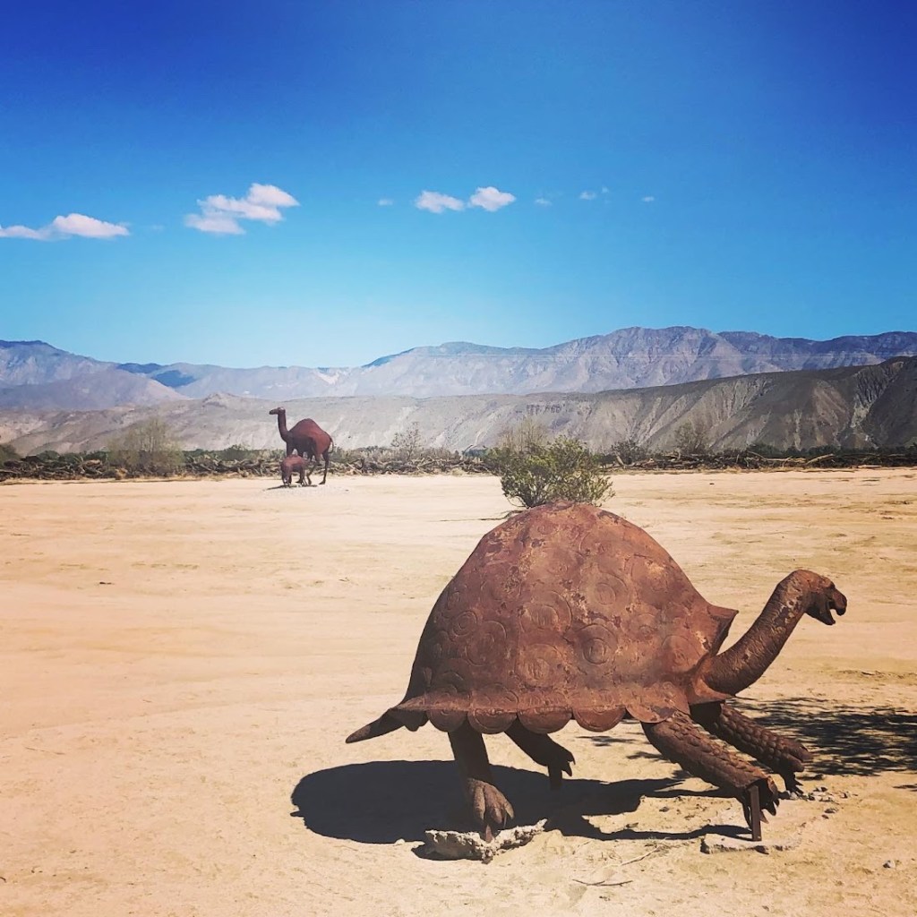 turtle sculpture with camels in background 